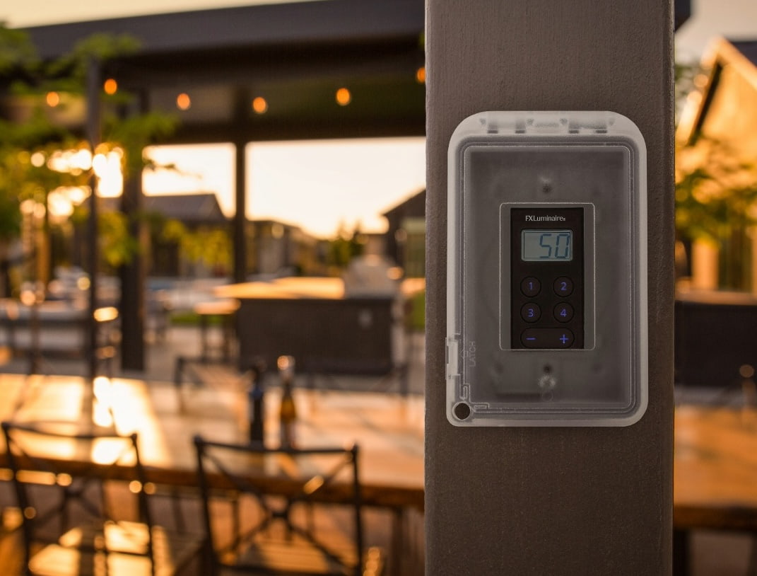 A digital outdoor lighting controller mounted on a post.